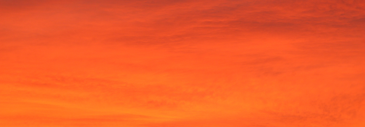 Stunning orange sky at sunset with vibrant hues and silhouetted clouds.