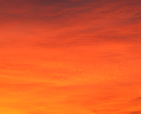 Stunning orange sky at sunset with vibrant hues and silhouetted clouds.