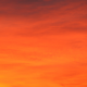 Stunning orange sky at sunset with vibrant hues and silhouetted clouds.